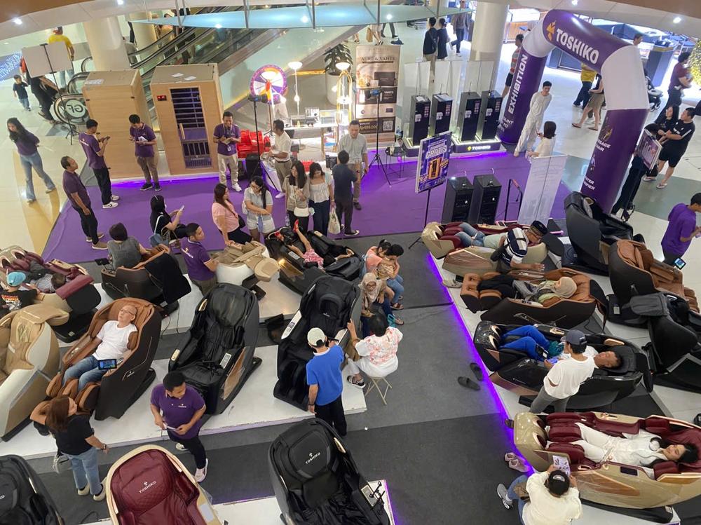 Visitors trying massage chairs across the showroom floor