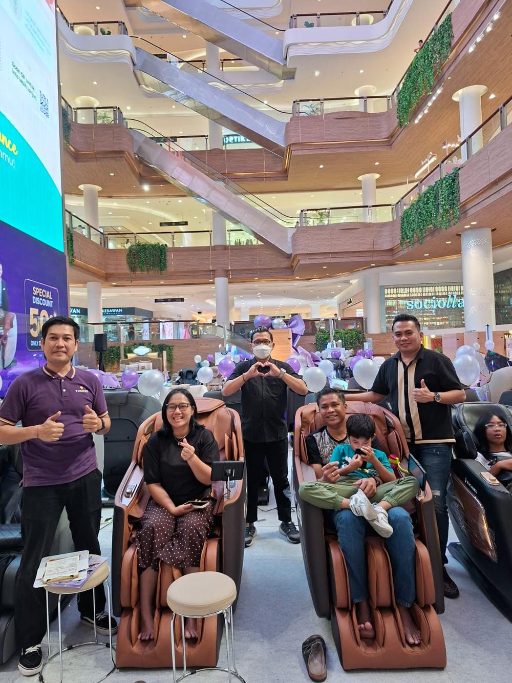 Toshiko staff with a family of customers seated in massage chairs